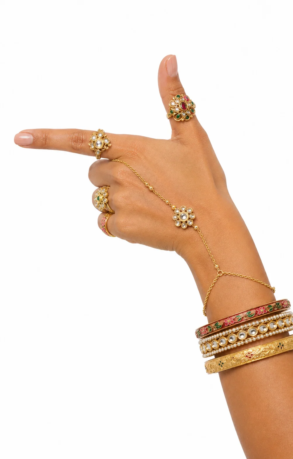 Pointing hand wearing gold kundan flower rings, a hand chain, and enamel and pearl bangles